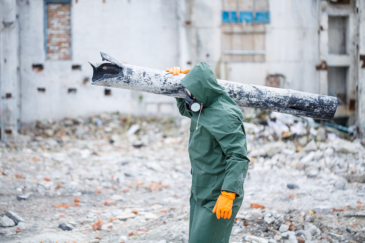 Ein Mann in Schutzmaske und Schutzkleidung entfernt Asbestrohre